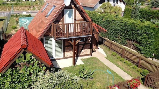 Ein Haus mit Schrägdach, Balkon und Garten.