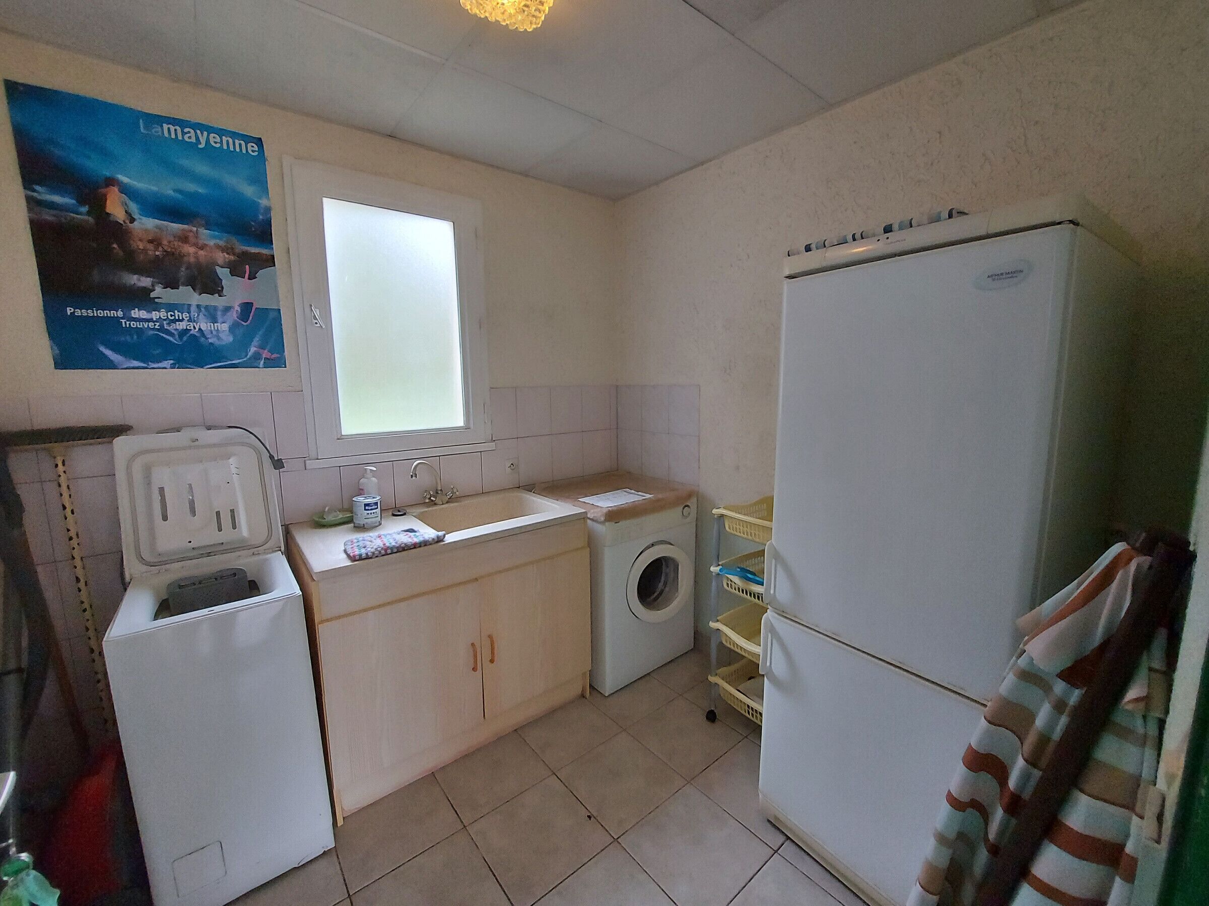 A compact kitchen with a washing machine, a refrigerator, a sink, and a window.