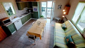 A compact kitchen with green cabinets, a dining table, and a sofa.