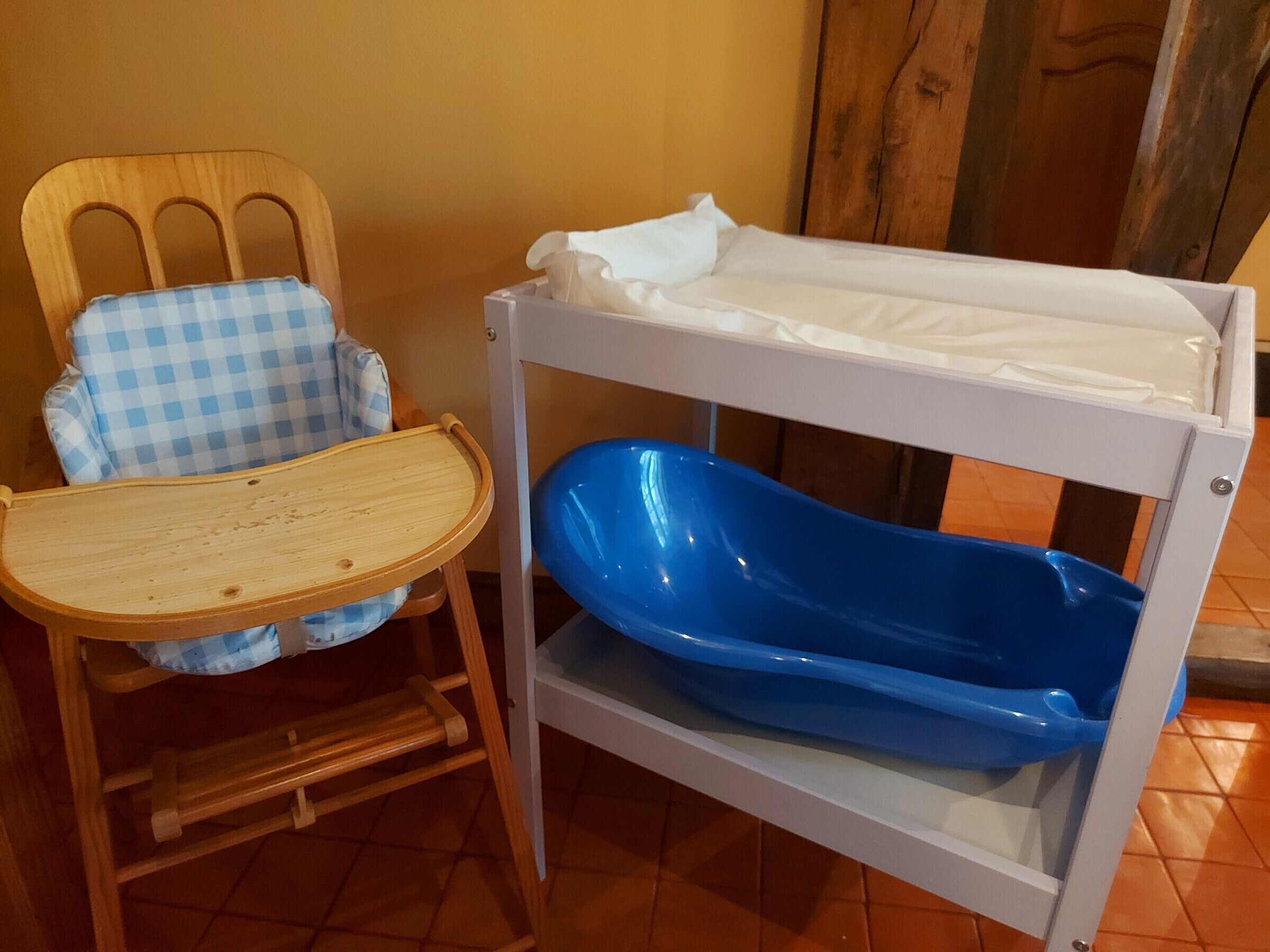 A wooden high chair with a blue checkered seat and a white tray.