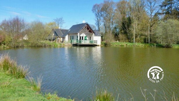 A house by a calm lake with a clear sky.