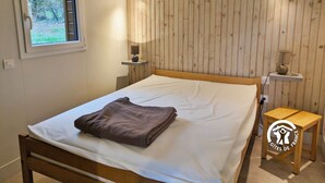 Ein Schlafzimmer mit einem hölzernen Bett, einem Fenster, zwei Nachttischlampen und einem kleinen Holztisch.