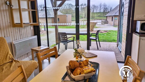 Ein Essbereich mit einem Tisch für zwei Personen, einem Korb mit Croissants und Blick auf die Terrassenförmige Außenanlage.
