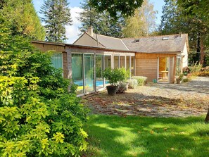 A house with a swimming pool, a covered patio, and a well-maintained garden.