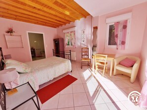A bedroom with a bed, a desk, a chair, and a window.
