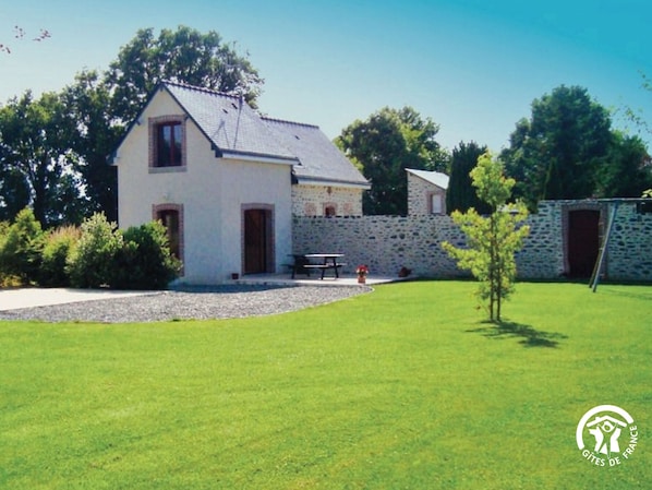 A two-story house with a stone wall and a small garden.