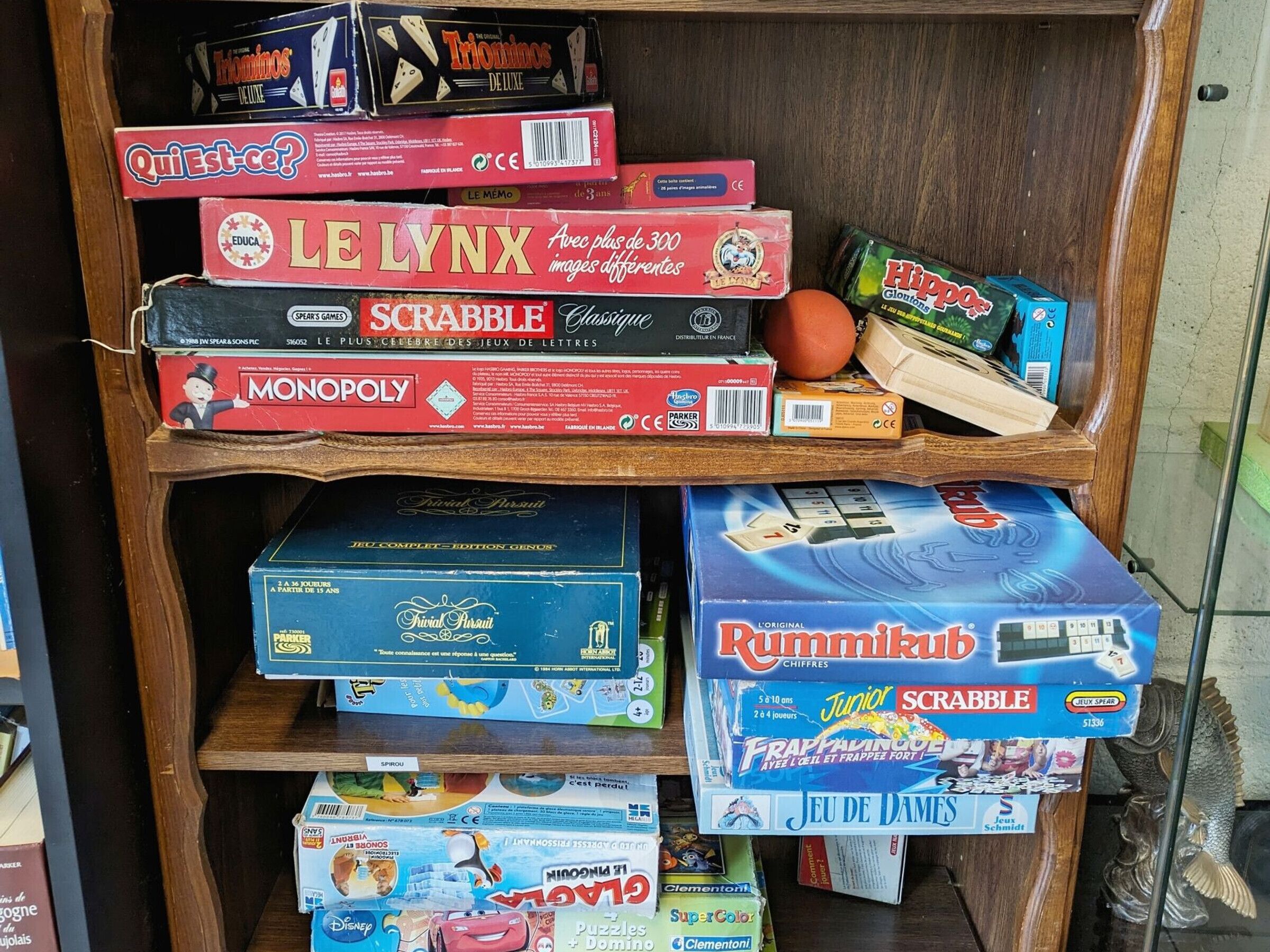 A shelf with various board games including Monopoly, Scrabble, and others.