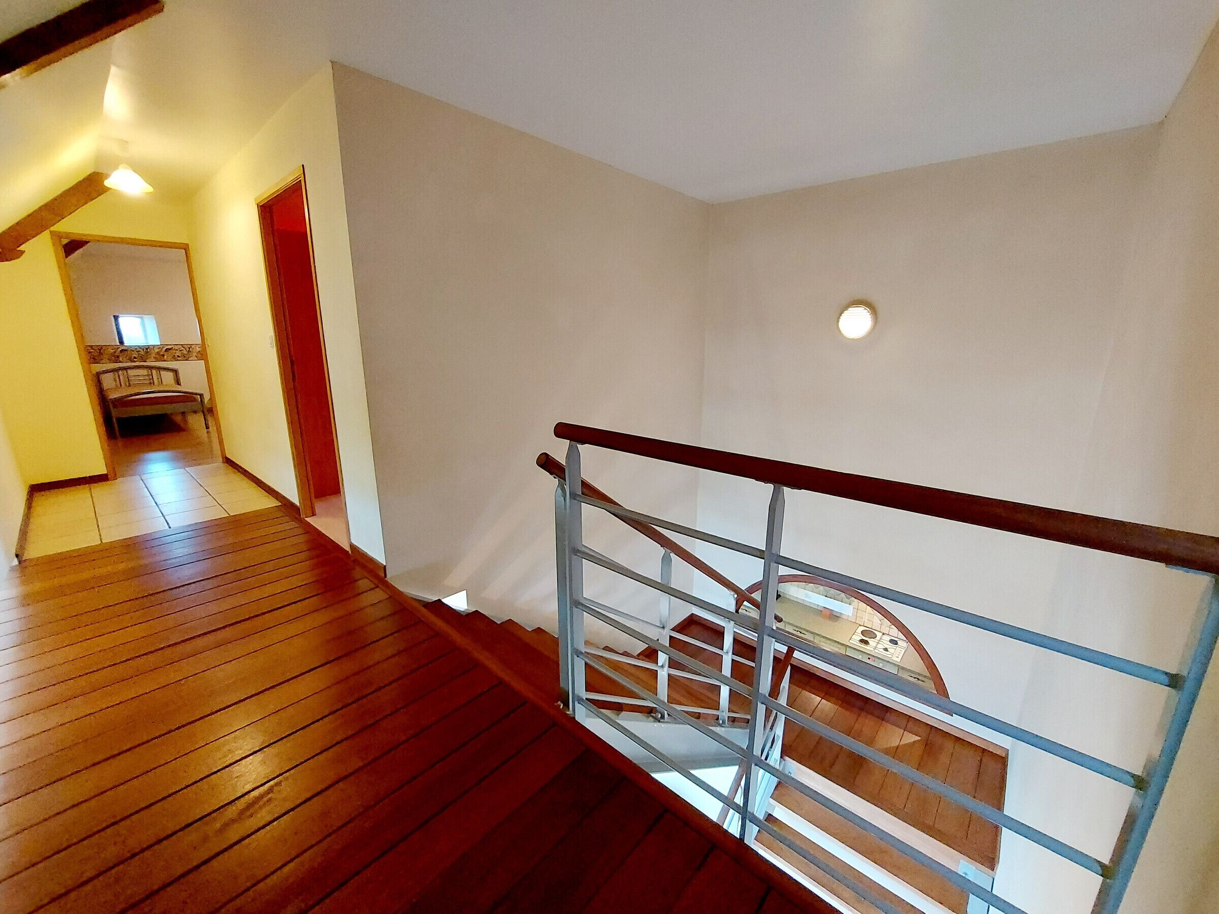 Eine Holztreppe mit Metallgeländer, das zu einer oberen Etage führt.