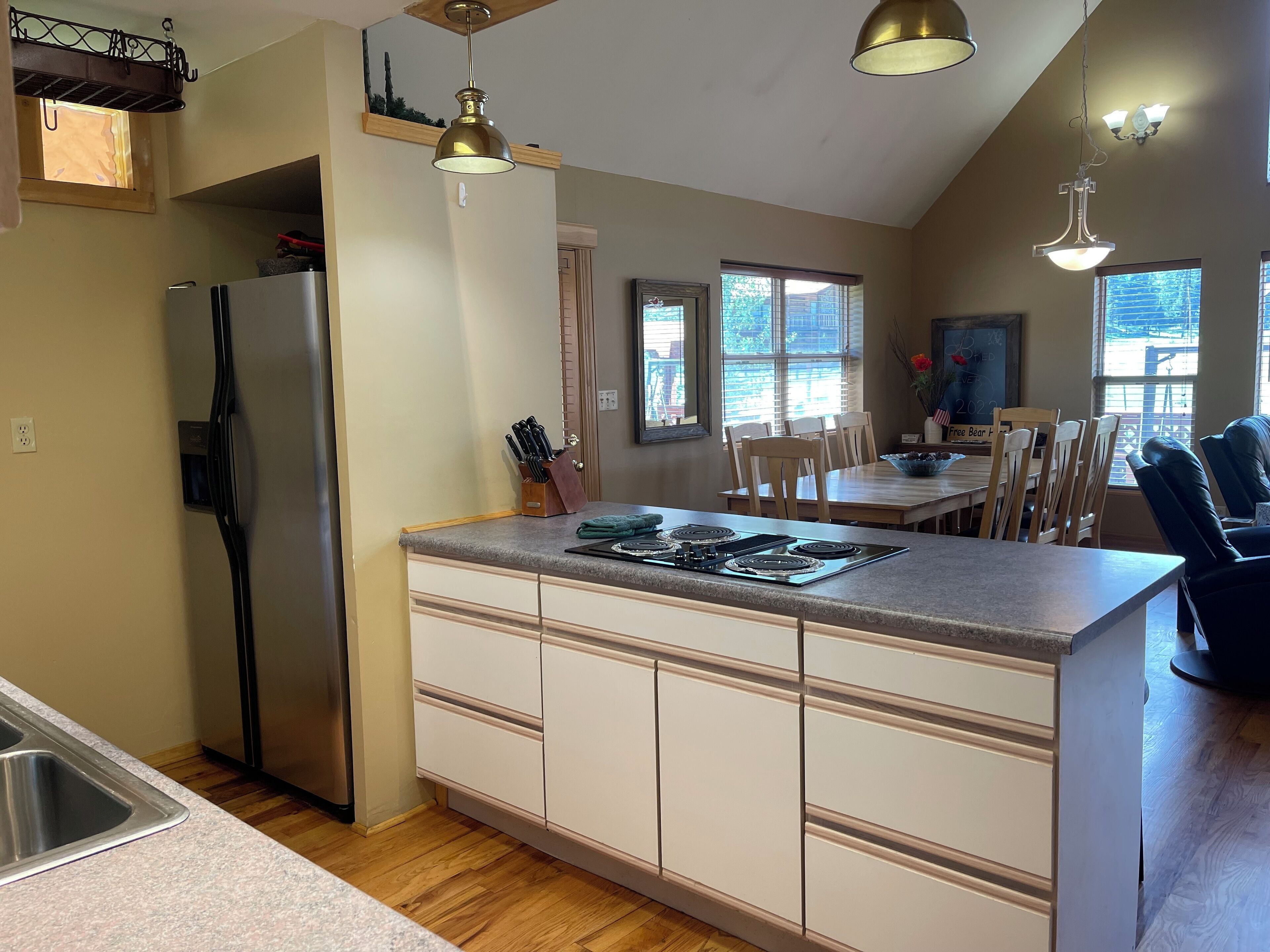 A kitchen with a refrigerator, stove, and dining area with chairs and a table.