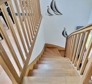 A wooden staircase with a railing, leading to a landing with a wall-mounted artwork.