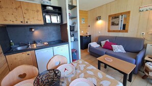Ein gemütlicher Wohnraum mit Küchenzeile, Essbereich und einer Sitzecke mit Sofa und Tisch.
