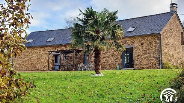 A stone building with a sloped roof, a covered patio, and a palm tree in the yard. - Spacious 6-Bedroom Cottage with Fishing Pond, Games & Garden - Sleeps 12-15 (Carelles)