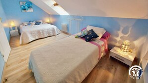 A bedroom with two beds, a skylight, and a bedside table with a lamp. - Spacious 6-Bedroom Cottage with Fishing Pond, Games & Garden - Sleeps 12-15 (Carelles)
