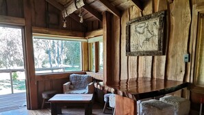 Un intérieur rustique en bois, avec un espace bar, des sièges et une grande fenêtre donnant sur l’extérieur.