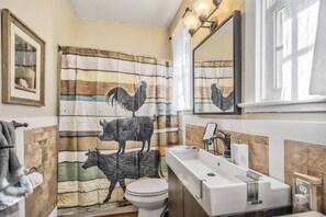 A bathroom with a rustic design, featuring a striped shower curtain with animal prints, a white sink, and a mirror above it. - Farm House in the Canyon Lands of Colorado, 2 BR, WiFi, Cable TV, Pets with Fee (Florence)