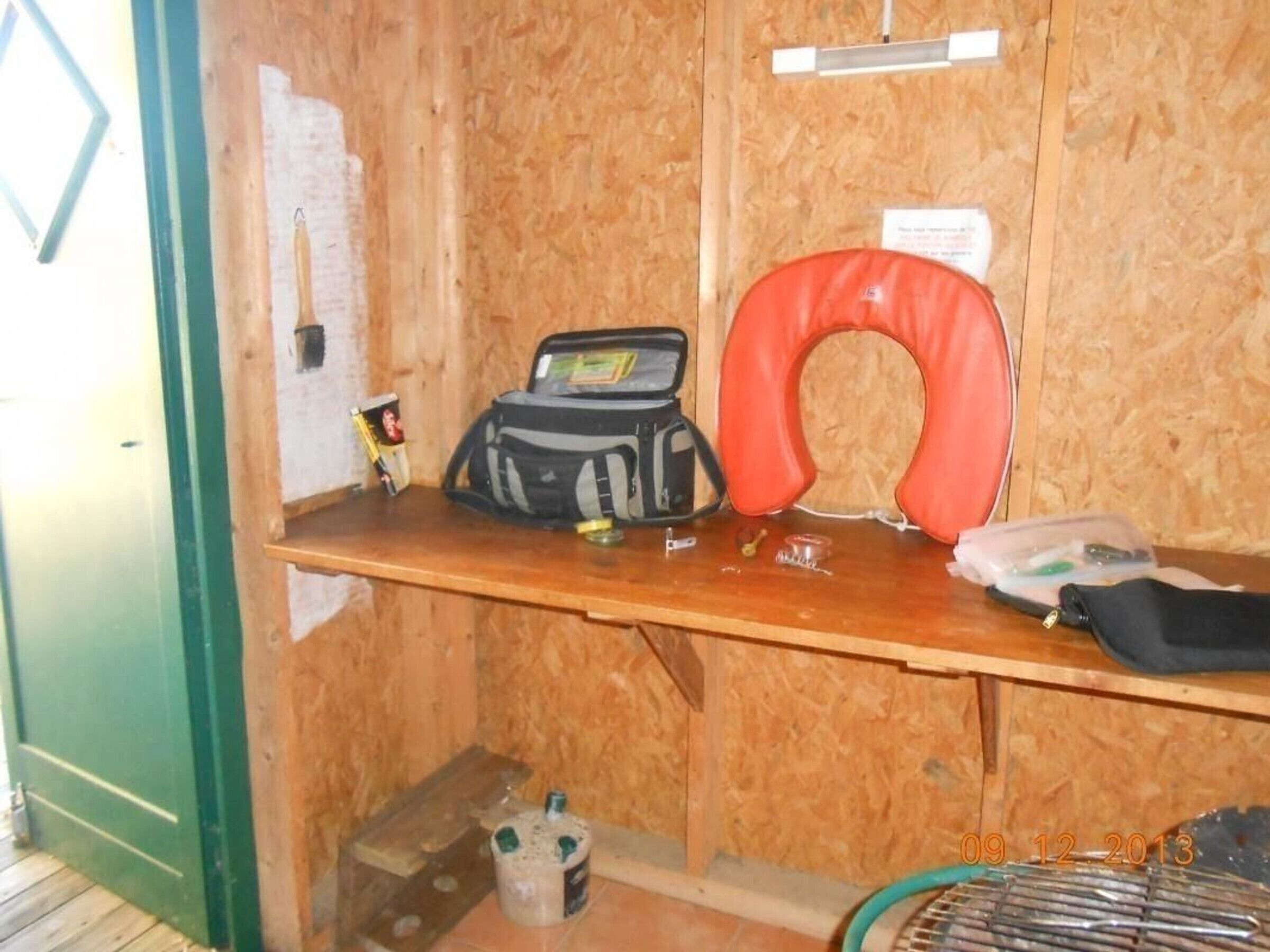 A wooden desk with a red neck pillow, a black bag, and a mug.