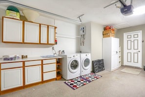Une buanderie équipée d’un lave-linge, d’un sèche-linge et d’un projecteur fixé au plafond.