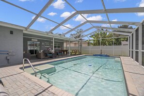 A covered swimming pool with a patio area, seating, and a view of the surrounding landscape. - Heated Pool, Private Backyard ~ Poolside Paradise (Pinellas Park)