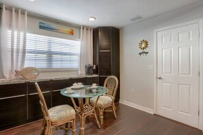 A dining area with a glass table, wicker chairs, and a window with blinds. - Heated Pool, Private Backyard ~ Poolside Paradise (Pinellas Park)
