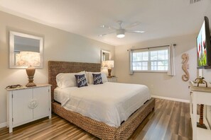 A bedroom with a large bed, a ceiling fan, and a window with blinds.