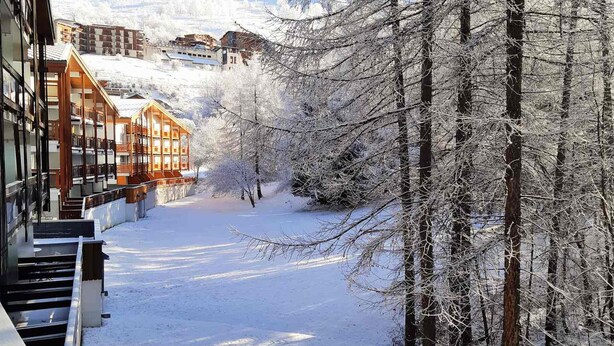 A snow-covered pathway flanked by buildings and trees, leading to a mountainous backdrop. - Quiet studio in Deux Alpes, ski access, pets allowed (Les Deux Alpes)