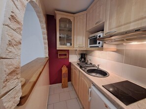 A compact kitchen with a stone archway, wooden cabinets, a microwave, a coffee maker, and a sink. - Quiet studio in Deux Alpes, ski access, pets allowed (Les Deux Alpes)