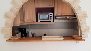A kitchen with a stone archway, a built-in toaster oven, a coffee maker, and a wooden tray. - Quiet studio in Deux Alpes, ski access, pets allowed (Les Deux Alpes)