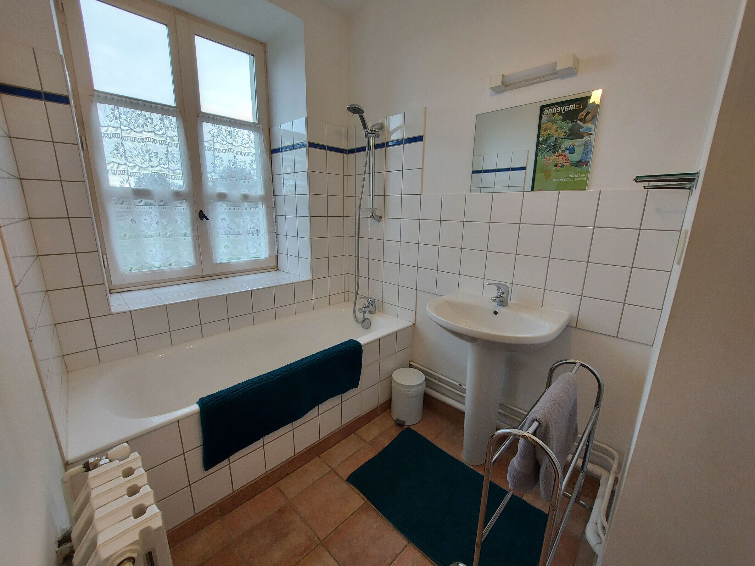 Une salle de bain avec une baignoire, un lavabo, une fenêtre et une douche.