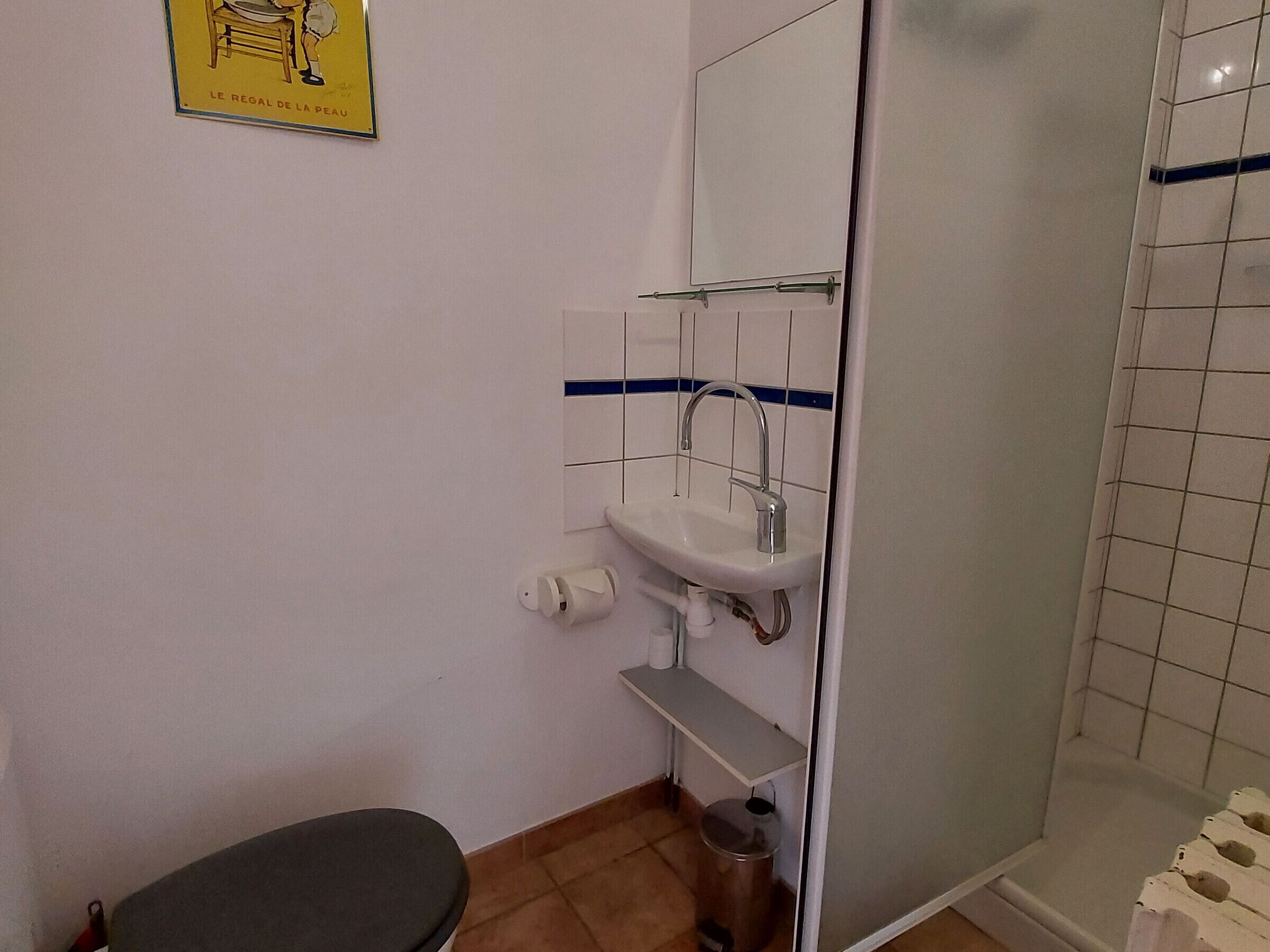 Et lille badeværelse med toilet, vask og brusebad.