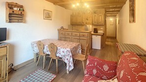 A cozy kitchen with wooden cabinets, a dining table with chairs, and a refrigerator.
