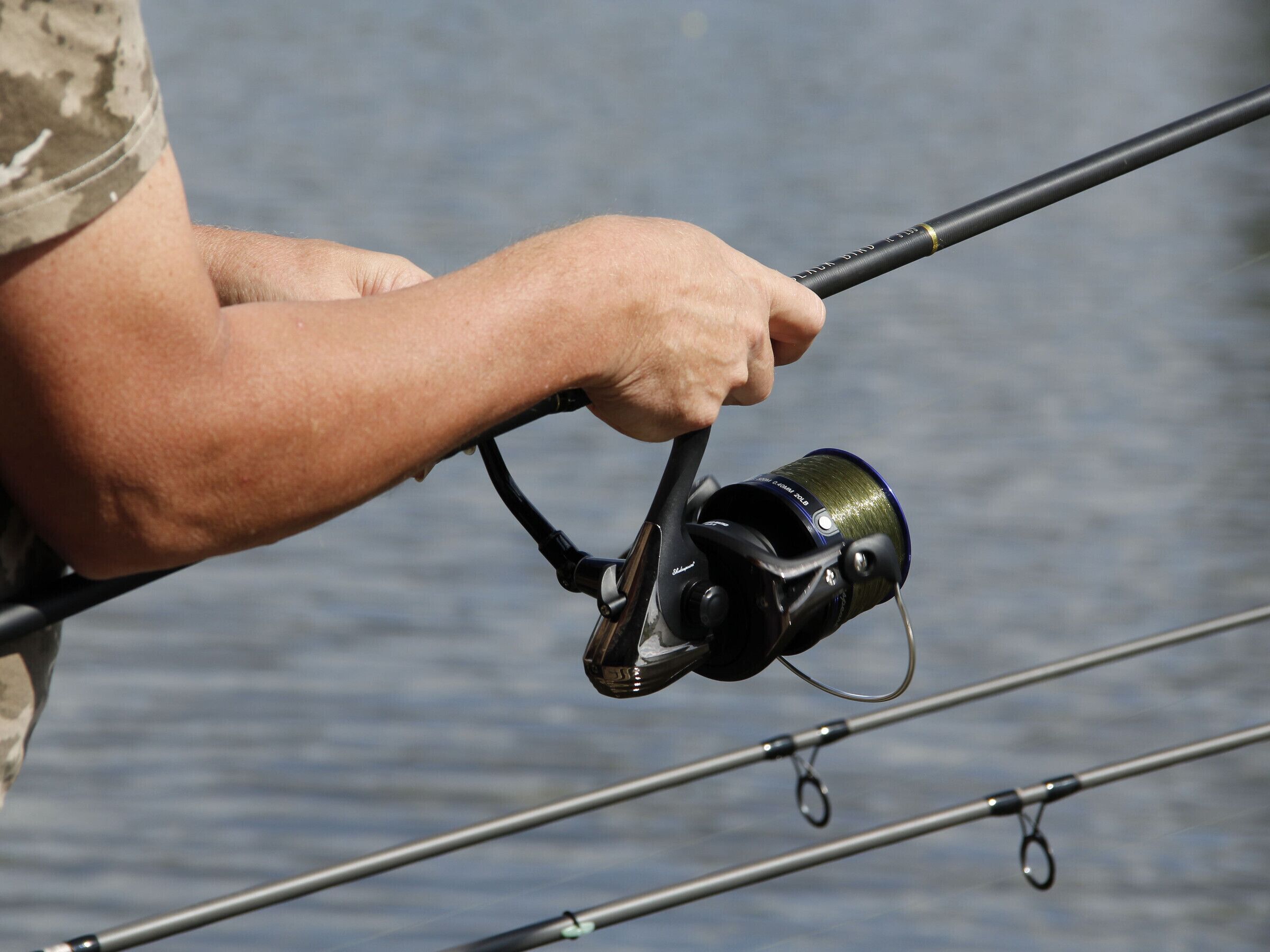 A person holding a fishing rod with a reel.