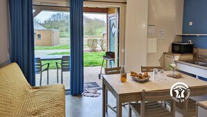 Une pièce comprenant une table à manger, des chaises, un coin cuisine avec un four à micro-ondes et une vue sur l’extérieur.