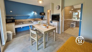 Une cuisine compacte équipée d’un four à micro-ondes, d’une machine à café et d’un petit coin repas avec une table et des chaises.