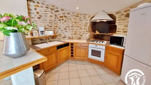 A kitchen with a stone wall, wooden cabinets, a built-in oven, and a gas stove.