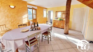 A dining area with a table set for four, wooden chairs, a wooden cabinet, and a large mirror above the sink.