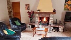 Een knusse woonkamer met een open haard, leren banken en een televisie.