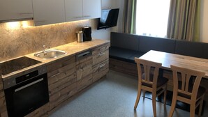 Eine kompakte Küche mit Einbauofen, einer Kaffeemaschine und einem Fernseher, der über der Arbeitsfläche angebracht ist.