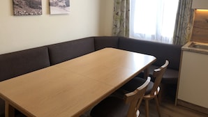 Ein Zimmer mit einem Holztisch, einem dunkelbraunen Sofa und zwei gerahmten Bildern an der Wand.