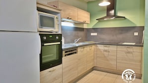 A kitchen with a microwave, oven, sink, and wooden cabinets. - Charming Countryside Retreat with Farm Experience and Nearby Forest (L'Huisserie)