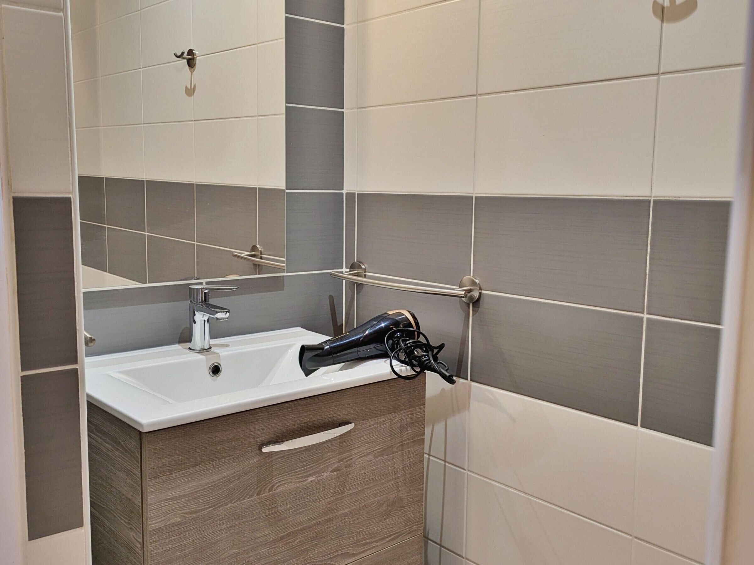 A bathroom with a white sink, a mirror, and a towel rack.