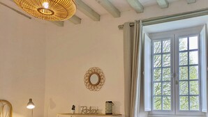 A bedroom with a bed, bedside table, lamp, and a window with curtains. - Charming Lakeside Manor with Garden, Ping-Pong, Biking, and Fishing (Cossé-le-Vivien)