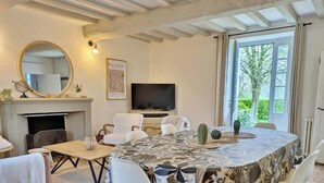 A dining room with a large table, chairs, a television, and a fireplace. - Charming Lakeside Manor with Garden, Ping-Pong, Biking, and Fishing (Cossé-le-Vivien)