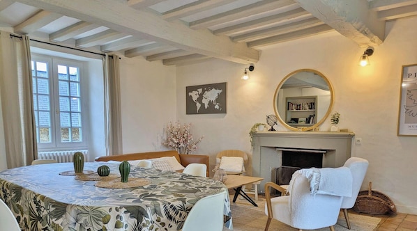 A room with a round table, chairs, a fireplace, a world map, and a mirror. - Charming Lakeside Manor with Garden, Ping-Pong, Biking, and Fishing (Cossé-le-Vivien)