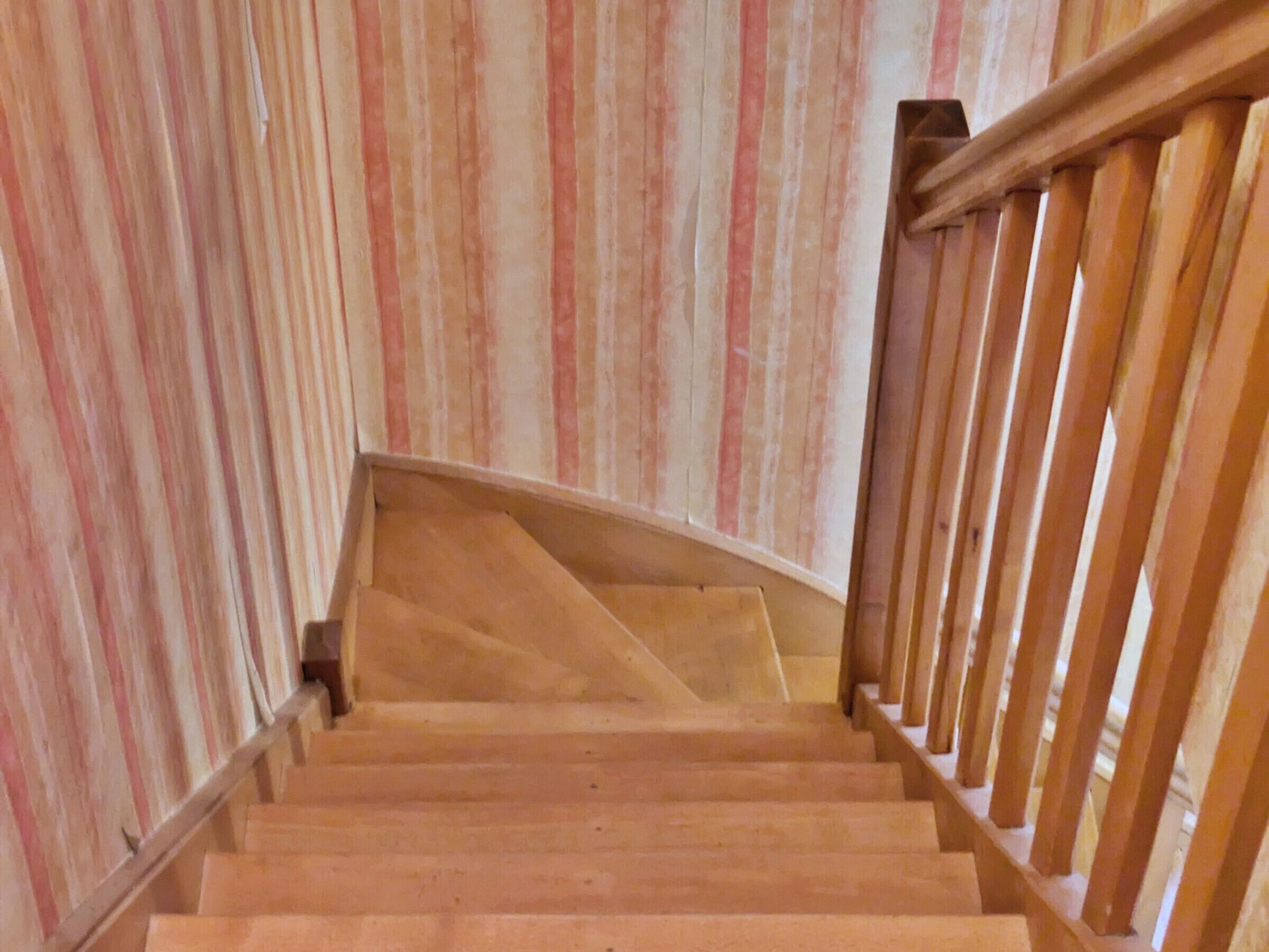 A wooden staircase with a handrail, leading to a landing.