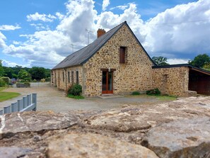 Un bâtiment en pierre avec un toit en pente, une porte en bois et un petit porche.