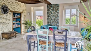 A dining area with a stone wall, a clock, and a view of the outside. - Cottage Nature & Comfort, 6 Pers., Accessible, Garden, Outdoor Games (Cossé-le-Vivien)