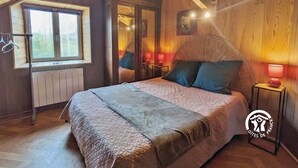 A cozy bedroom with a large bed, a window, and a door leading to another room.