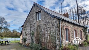 A stone building with a sloped roof, a chimney, and a satellite dish.