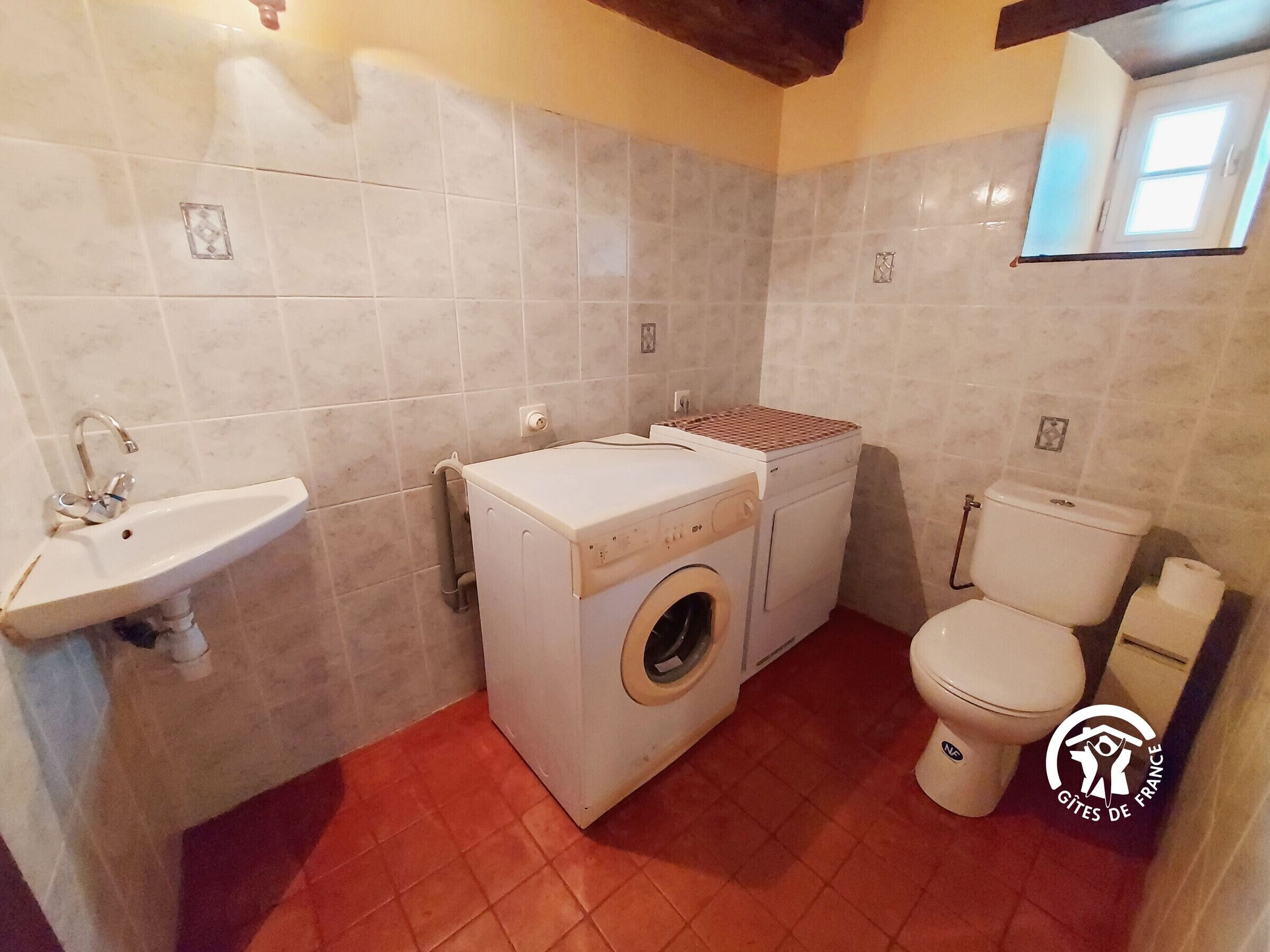 Un baño pequeño con lavamanos, lavadora e inodoro.