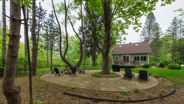 A house with a paved patio surrounded by trees.